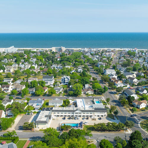 Aerial view of a coastal town with numerous houses, greenery, and a water tower labeled 