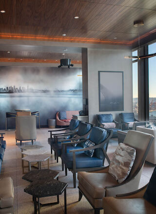 A modern lounge with comfortable seating, large windows with a city view, and ambient lighting reveals a relaxing atmosphere.