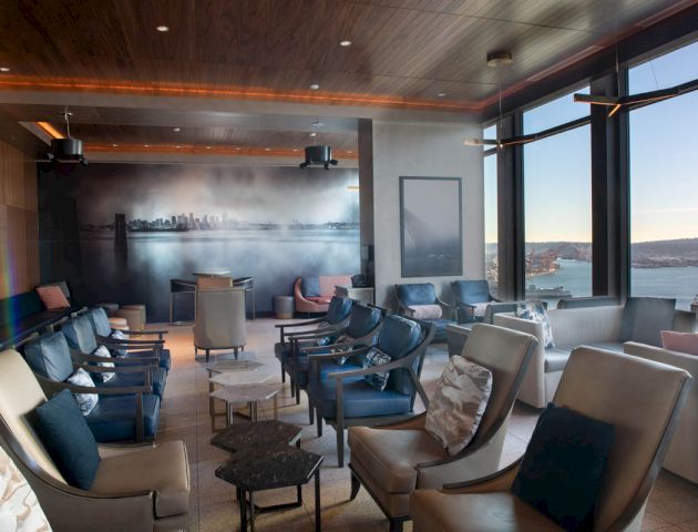 A modern lounge with comfortable seating, large windows with a city view, and ambient lighting reveals a relaxing atmosphere.